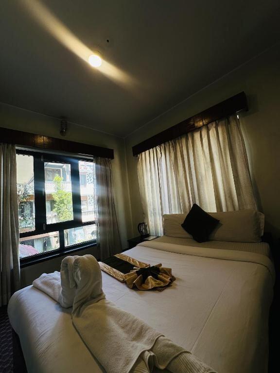 AC room with a made-up double bed and folded towels at Boudha Orange Hotel
