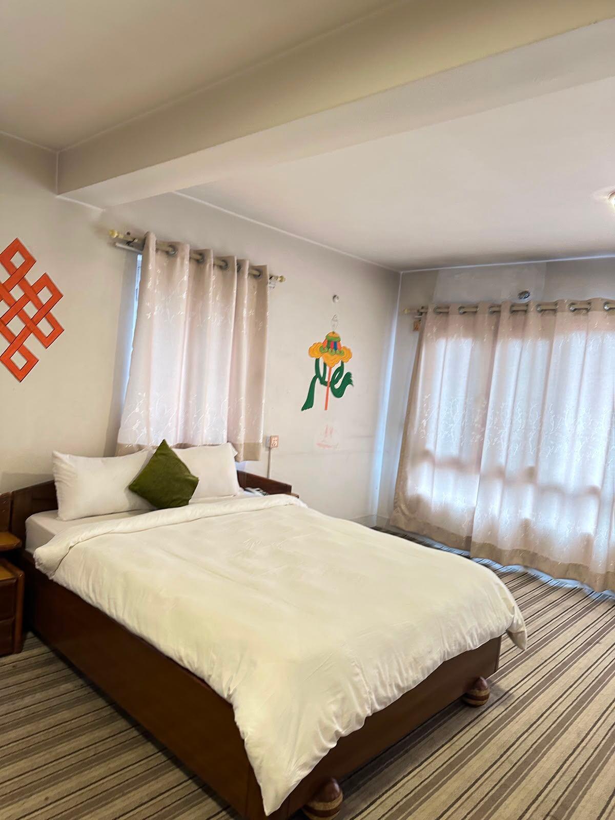 Spacious apartment-style room with orange endless-knot wall art at Boudha Orange Hotel