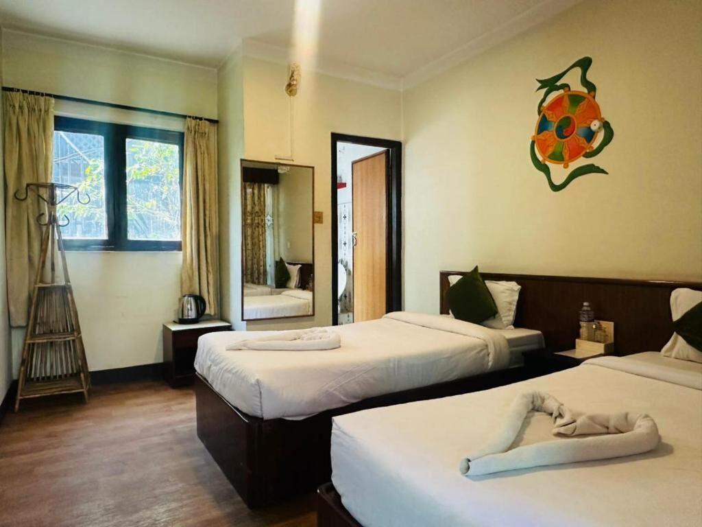 Non-AC twin room with traditional Buddhist wall art at Boudha Orange Hotel